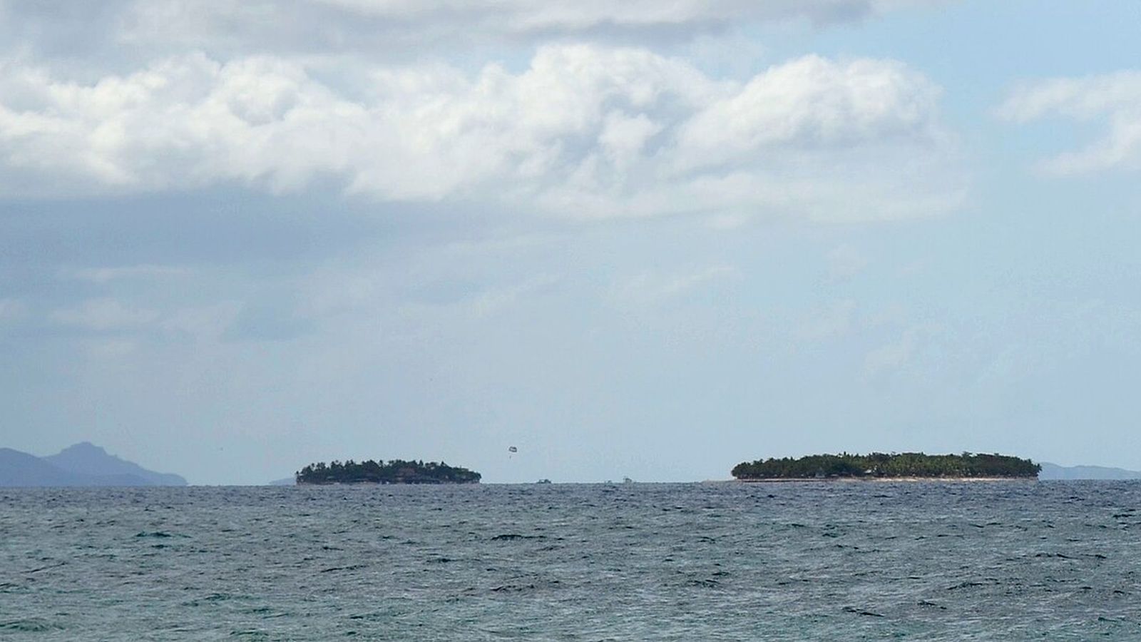 Twee kleine eilanden van de Mamanuca-groep aan de horizon boven een donkerblauwe zee