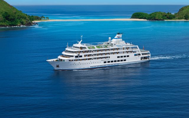 Klein cruiseschip vaart door diepblauw water tussen groene eilanden in de Yasawa-groep