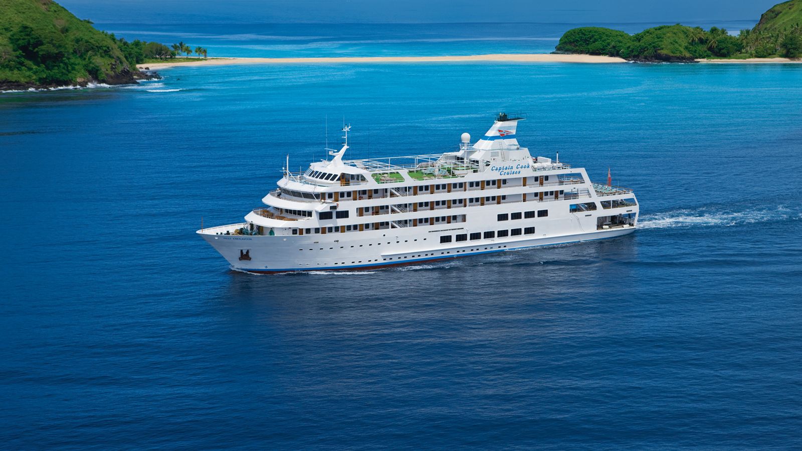 Klein cruiseschip vaart door diepblauw water tussen groene eilanden in de Yasawa-groep