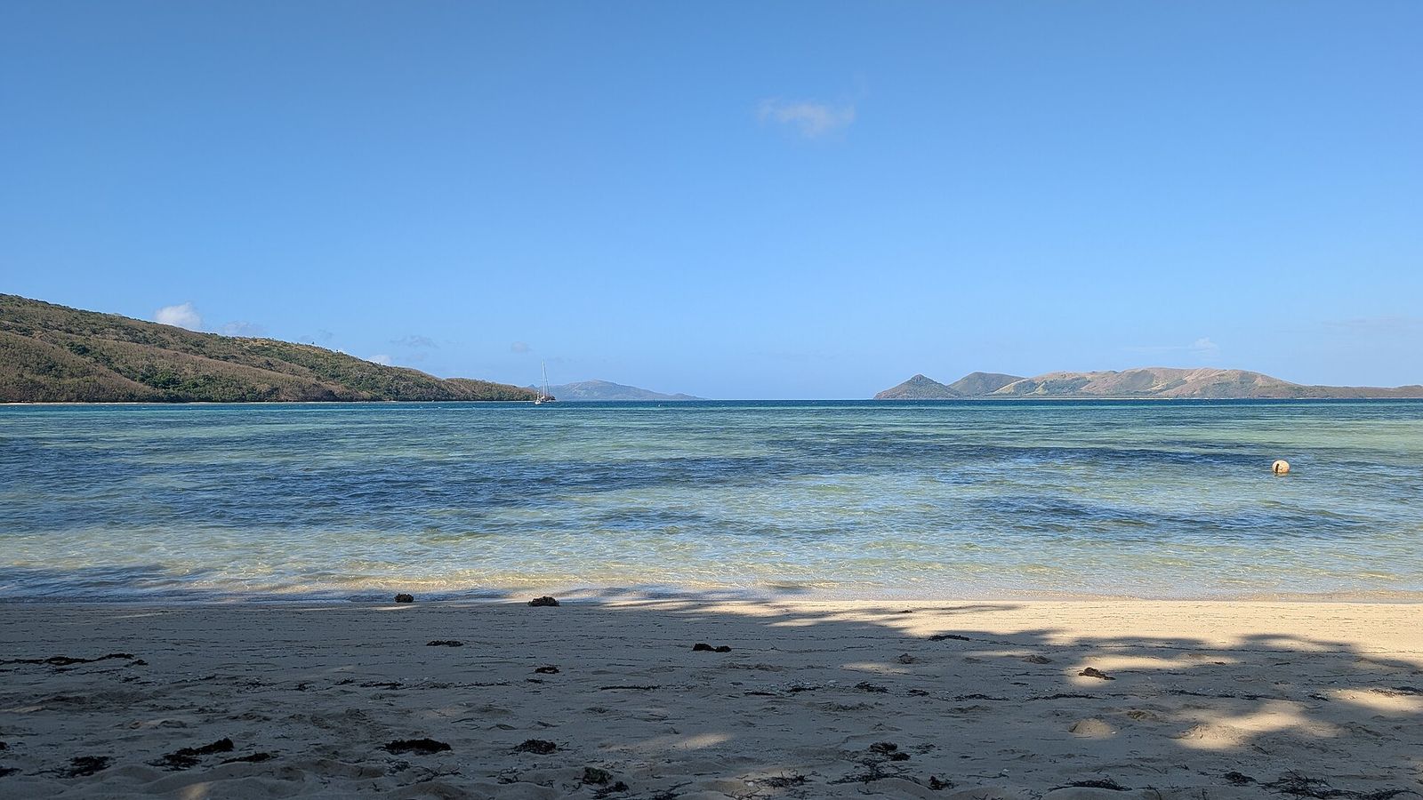 Rustig zandstrand met helder water en eilanden aan de horizon aan de noordkant van Naviti