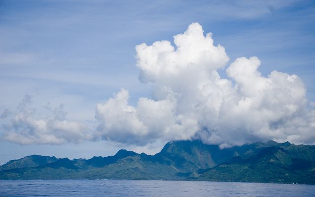 Het bergsilhouet van Moorea onder hoge stapelwolken, gezien vanaf zee