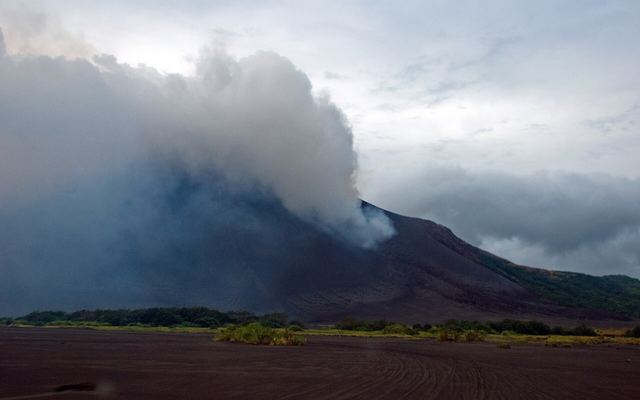 Asvlakte aan de voet van de vulkaan Mount Yasur op Tanna, Vanuatu, met een rookpluim boven de krater