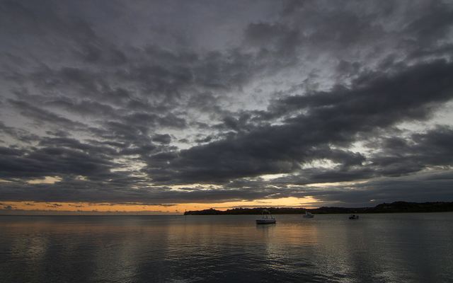 Zonsondergang met bewolking boven een baai bij de Coral Coast