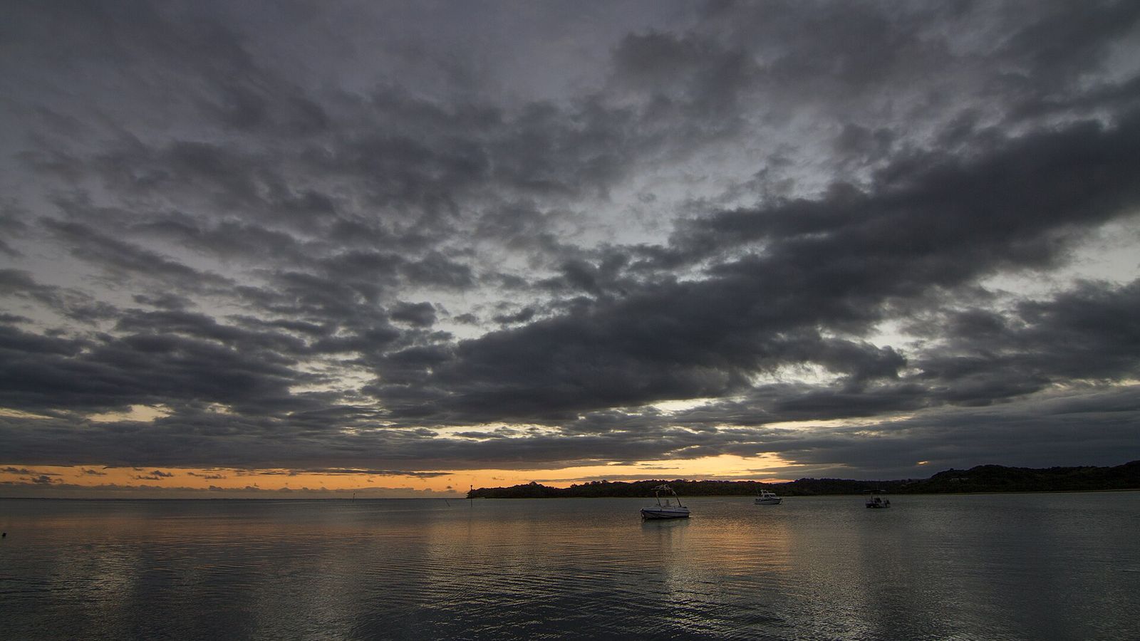 Zonsondergang met bewolking boven een baai bij de Coral Coast